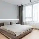 Un lit aux teintes grises dans une chambre lumineuse