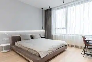 Un lit aux teintes grises dans une chambre lumineuse