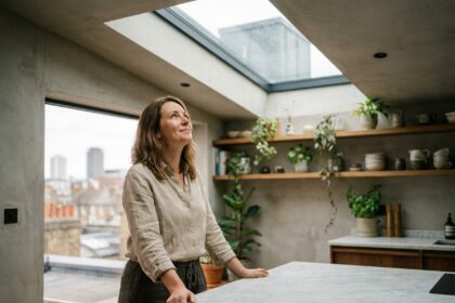 Femme dans une cuisine urbaine moderne sous une verrière de toit laissant entrer la lumière naturelle