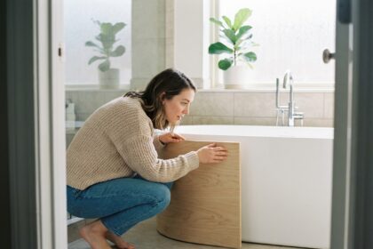 Femme examinant un panneau en bois près d'une baignoire moderne