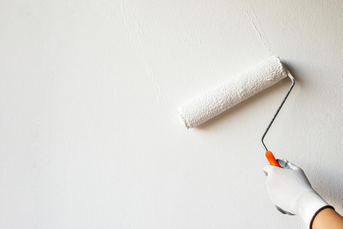 Gros plan sur la main d'un peintre professionnel appliquant de la peinture sur un mur à l'aide d'un rouleau